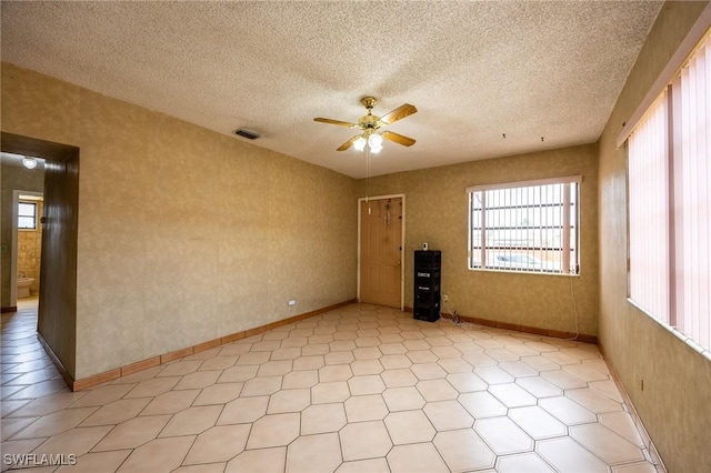 unfurnished room featuring baseboards, ceiling fan, visible vents, and a textured ceiling