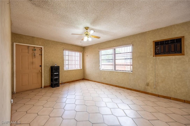 spare room with ceiling fan, a textured ceiling, and baseboards