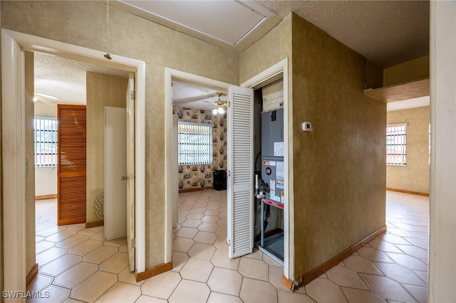 corridor featuring a textured ceiling, baseboards, and wallpapered walls