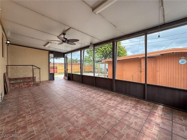 unfurnished sunroom with ceiling fan