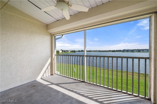 unfurnished sunroom with vaulted ceiling, a ceiling fan, and a water view