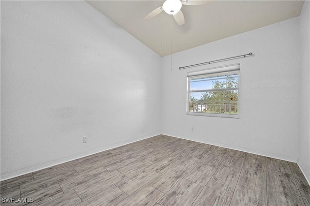 spare room with wood finished floors, a ceiling fan, baseboards, and lofted ceiling