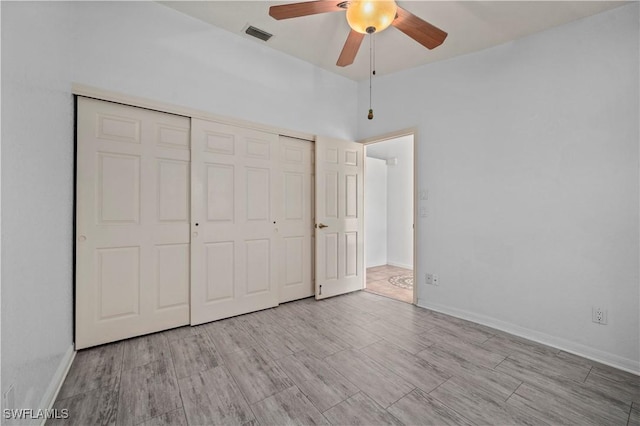 unfurnished bedroom featuring wood finished floors, visible vents, a closet, and baseboards