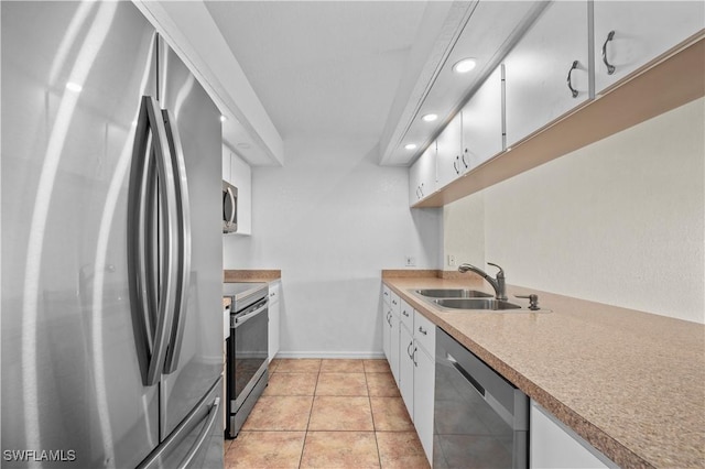 kitchen with baseboards, light tile patterned floors, appliances with stainless steel finishes, white cabinetry, and a sink