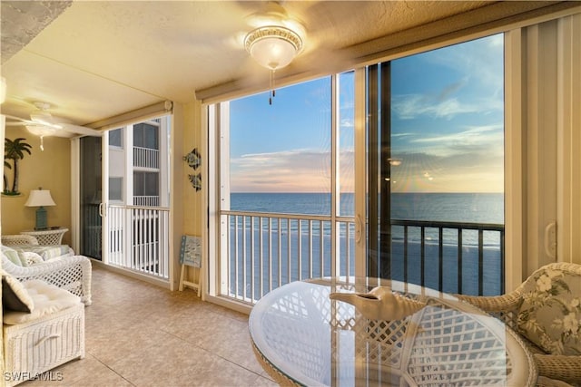 sunroom featuring a ceiling fan, a healthy amount of sunlight, and a water view