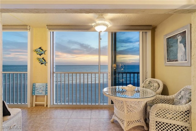 dining space featuring tile patterned floors, expansive windows, and a water view