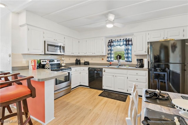 kitchen featuring light countertops, light wood-style flooring, a sink, ceiling fan, and black appliances