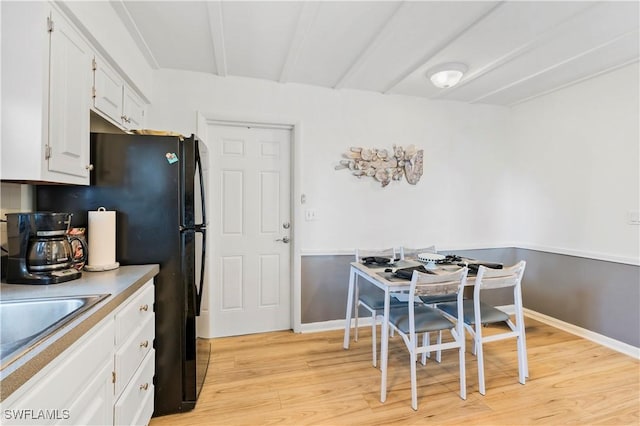 kitchen featuring light wood-style floors, white cabinets, a sink, and baseboards