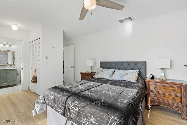 bedroom featuring light wood-style floors, a closet, visible vents, and ensuite bath