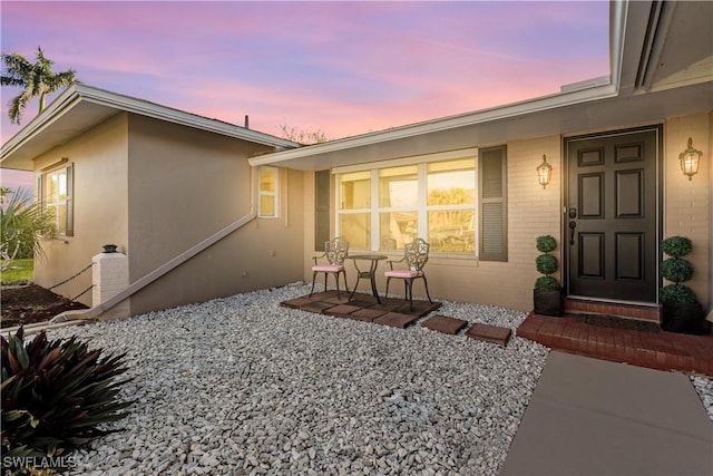 entrance to property featuring brick siding and stucco siding