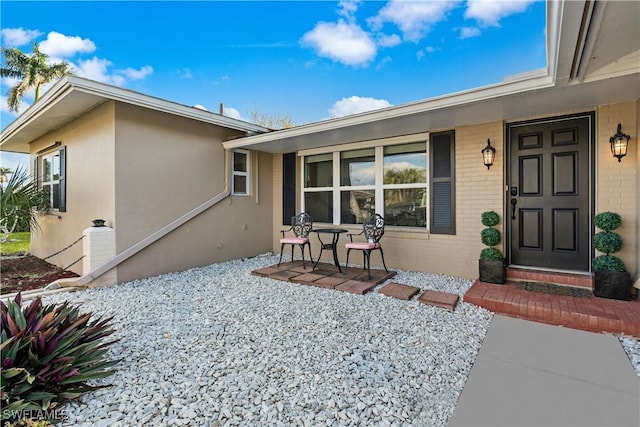 doorway to property with brick siding and stucco siding