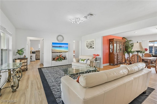 living area featuring light wood-style flooring, visible vents, and baseboards