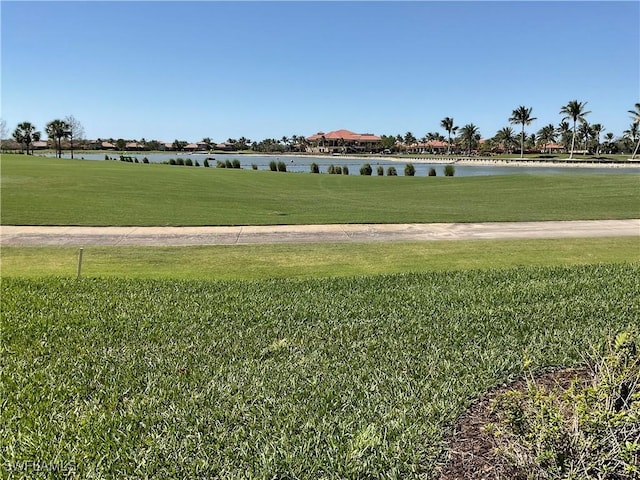 surrounding community with a water view and a yard