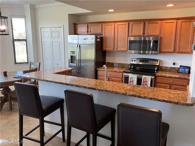 kitchen with brown cabinetry, a breakfast bar area, stainless steel appliances, and crown molding