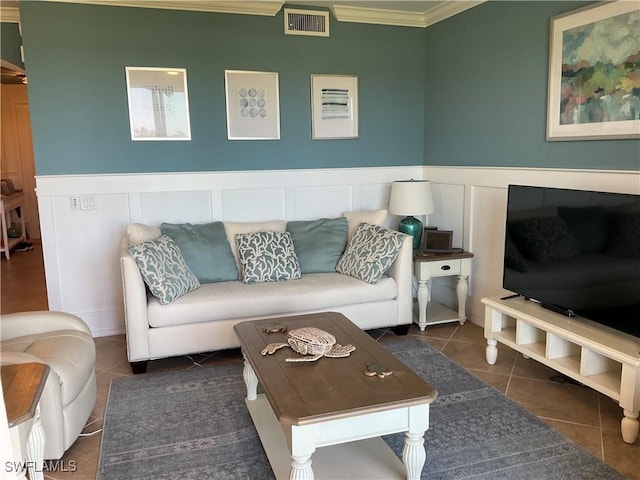 living room featuring a wainscoted wall, crown molding, visible vents, a decorative wall, and tile patterned flooring