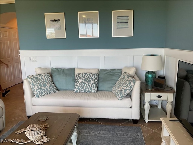 living area with a wainscoted wall, tile patterned flooring, and a decorative wall