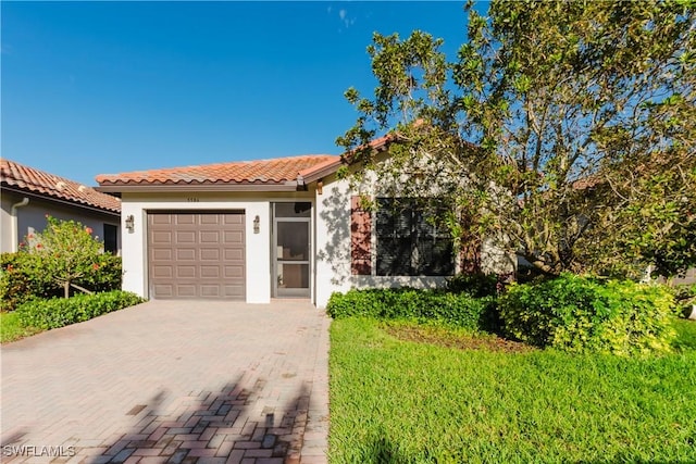 view of front facade featuring an attached garage, stucco siding, a front lawn, a tile roof, and decorative driveway