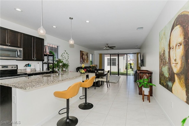 kitchen with light stone countertops, visible vents, a breakfast bar, a sink, and stainless steel appliances