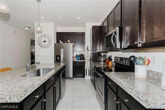 kitchen featuring decorative light fixtures, light tile patterned floors, light stone counters, appliances with stainless steel finishes, and a sink