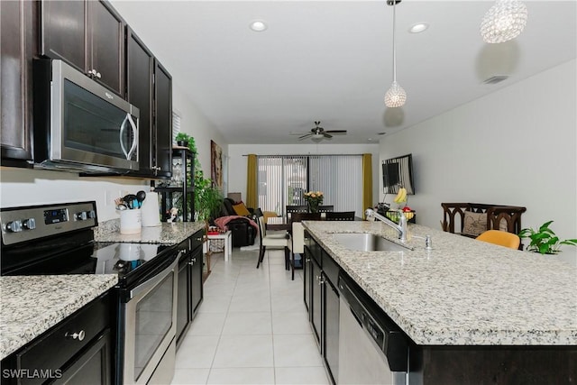 kitchen featuring pendant lighting, a kitchen island with sink, a sink, stainless steel appliances, and light tile patterned flooring