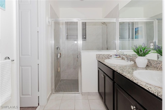 bathroom with tile patterned floors, double vanity, a stall shower, and a sink