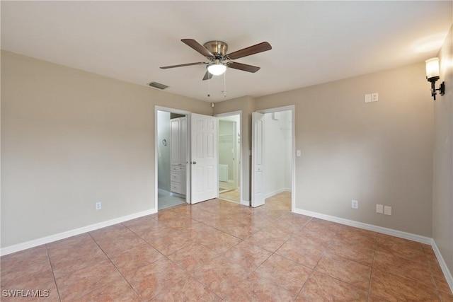 unfurnished bedroom with light tile patterned floors, baseboards, visible vents, ensuite bathroom, and a walk in closet