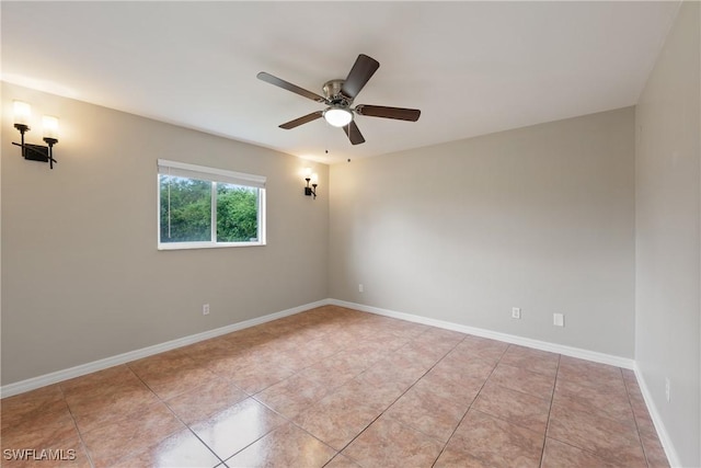 spare room featuring light tile patterned floors, ceiling fan, and baseboards