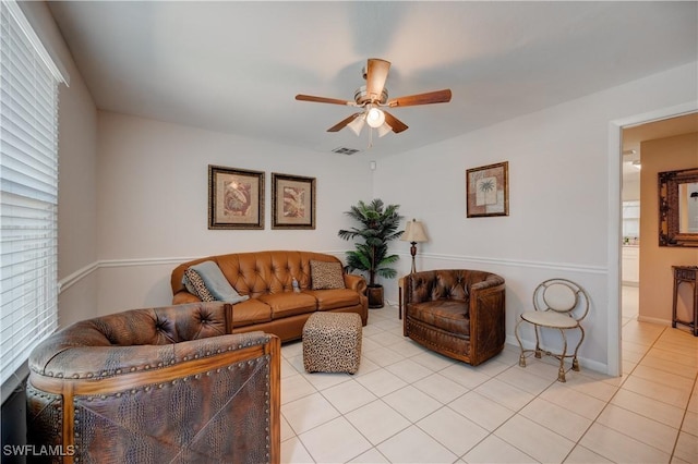 living room featuring light tile patterned floors, visible vents, baseboards, and ceiling fan