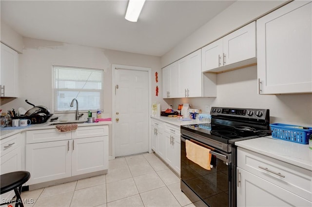 kitchen with white cabinets, stainless steel range with electric cooktop, light countertops, and a sink