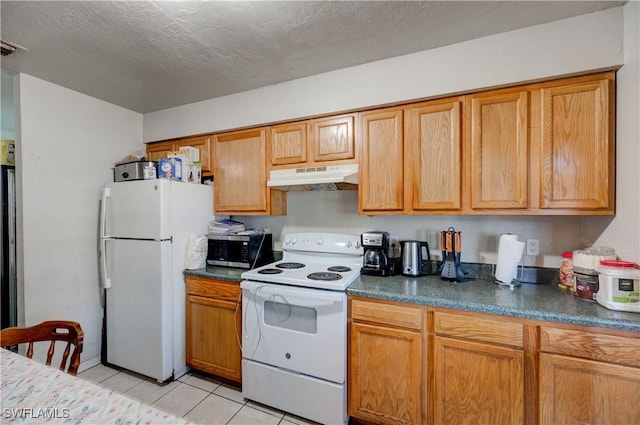 kitchen featuring under cabinet range hood, light tile patterned floors, white appliances, and dark countertops