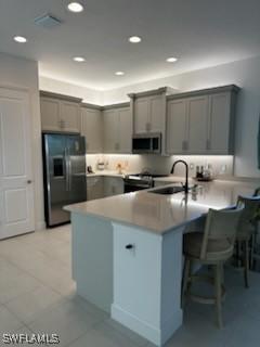 kitchen featuring gray cabinetry, stainless steel microwave, black fridge with ice dispenser, and a sink