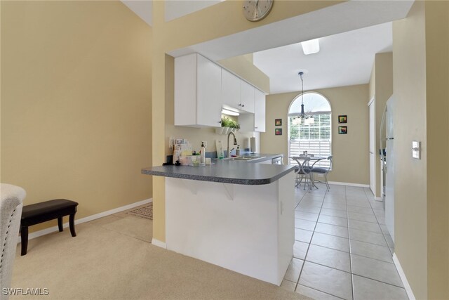 22741 Sandy Bay Dr Unit 201, Estero, FL 33928 - kitchen with dark countertops, a peninsula, light tile patterned flooring, white cabinets, and a sink