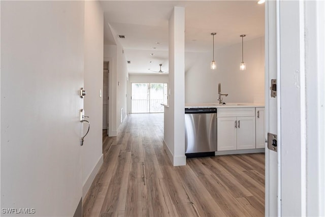 kitchen with a sink, visible vents, light wood-type flooring, dishwasher, and pendant lighting