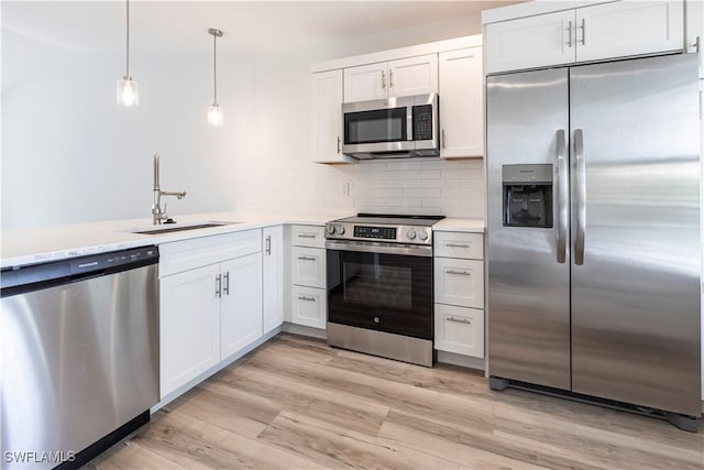 kitchen featuring light wood-style floors, appliances with stainless steel finishes, light countertops, and a sink