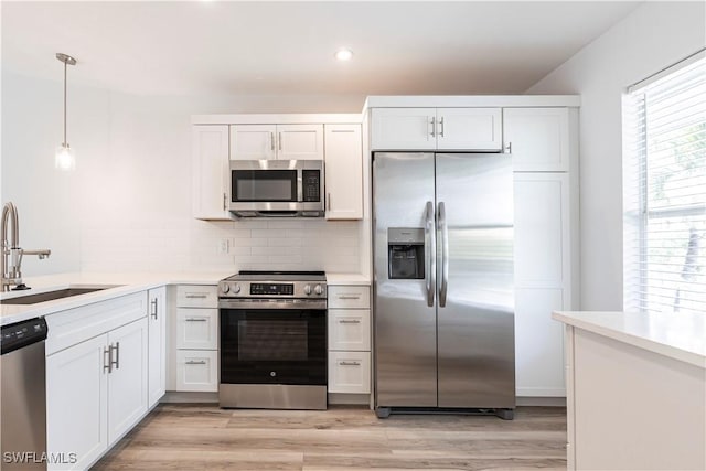 kitchen with stainless steel appliances, light countertops, white cabinetry, and a sink