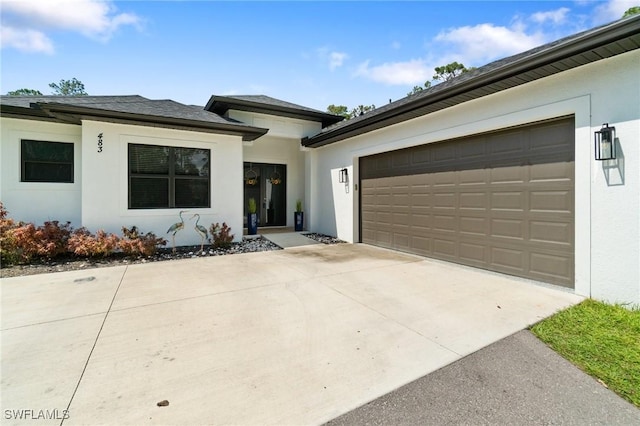 view of front of home featuring concrete driveway, an attached garage, and stucco siding