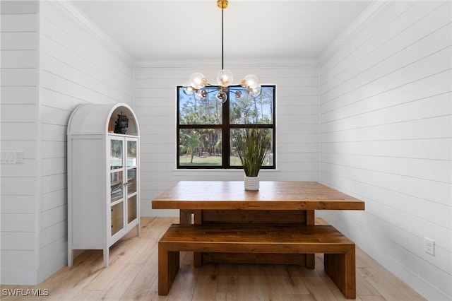 unfurnished dining area with a chandelier, ornamental molding, and light wood finished floors