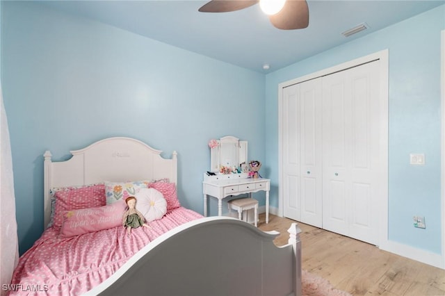 bedroom with baseboards, visible vents, ceiling fan, wood finished floors, and a closet