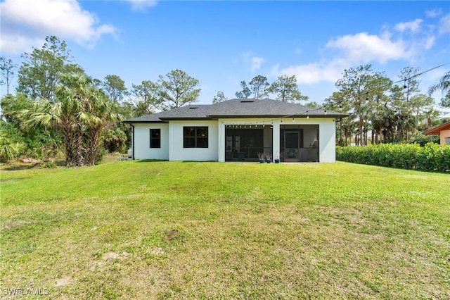 rear view of property with a sunroom, a lawn, and stucco siding