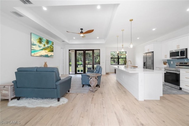 kitchen featuring visible vents, open floor plan, a tray ceiling, stainless steel appliances, and a sink