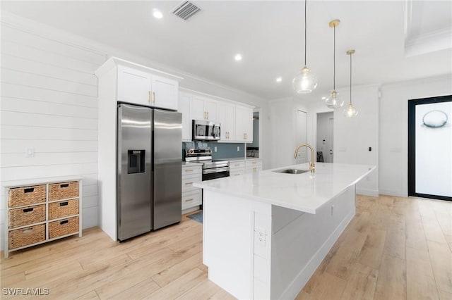 kitchen featuring stainless steel appliances, a sink, visible vents, light wood-style floors, and ornamental molding