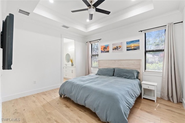 bedroom featuring a raised ceiling, visible vents, crown molding, and light wood-style flooring