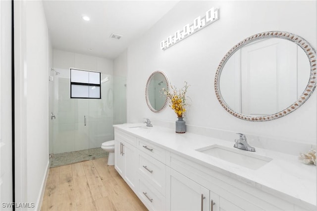 bathroom featuring a stall shower, a sink, toilet, and wood finished floors