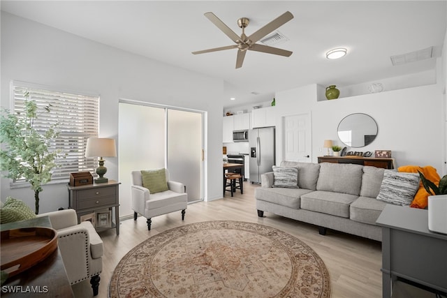 living area featuring light wood-style flooring, visible vents, and a ceiling fan