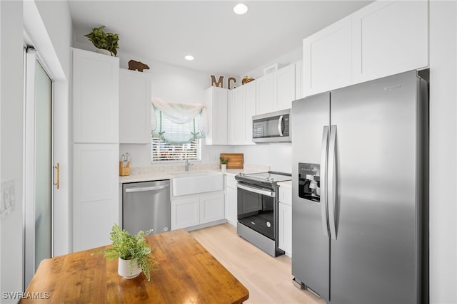 kitchen with stainless steel appliances, a sink, white cabinetry, and recessed lighting