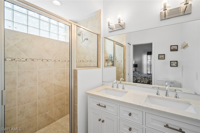 ensuite bathroom with connected bathroom, a sink, a shower stall, and double vanity