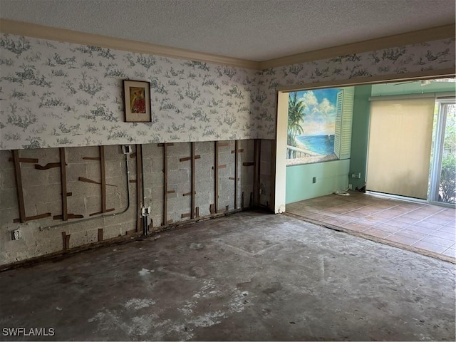 spare room with a textured ceiling and wallpapered walls