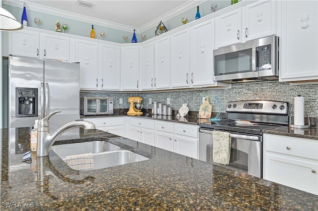 kitchen with backsplash, appliances with stainless steel finishes, ornamental molding, white cabinets, and a sink