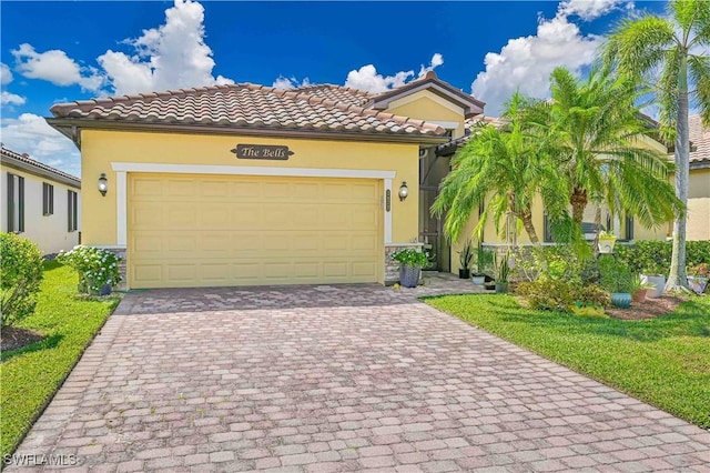 mediterranean / spanish-style house featuring a garage, decorative driveway, a tiled roof, and stucco siding