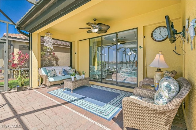 view of patio featuring glass enclosure, ceiling fan, and an outdoor hangout area